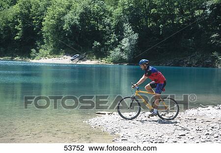 Side profile of man sitting on bicycle at lakeside, Lago di Tenno, Riva, Trentino, Italy View Large Photo Image Stock Image - Side profile of man sitting on bicycle at lakeside, Lago di Tenno, Riva, Trentino, Italy . Fotosearch