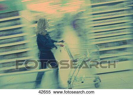 Side view of a woman pushing a trolley in a supermarket, Germany, Europe View Large Photo Image Stock Photography - Side view of a woman pushing a trolley in a supermarket, Germany, Europe . Fotosearch