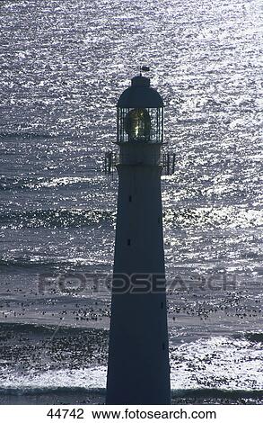 Stock Image - Silhouette of lighthouse at coast, Kommetjie, Cape Town, South Africa . Fotosearch