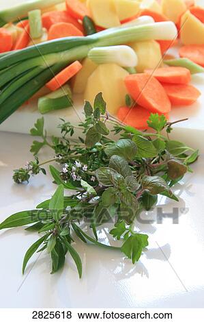 Stock Photo - Slices of carrot with potato and spring onion on cutting board . Fotosearch