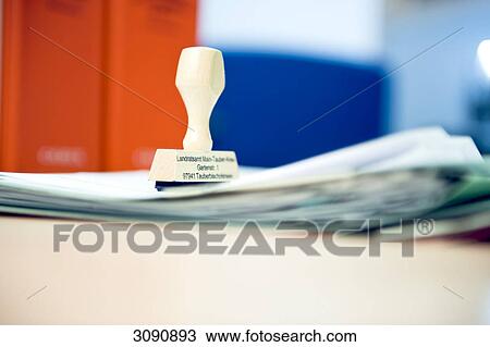 Stock Image - Stamp on a stack of paper, close-up . Fotosearch