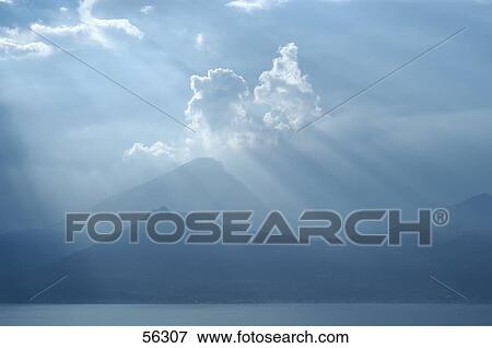 Stock Photo - Sun rays emitting on mountain range, Lake Garda, Malcesine, Veneto, Italy . Fotosearch