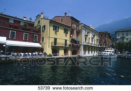 Stock Photo - Tourists at outdoor cafe at harbor, Lago di Garda, Veneto, Italy . Fotosearch
