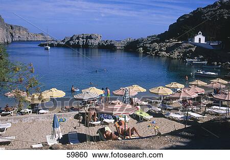 Stock Image - Tourists relaxing on coast, Lidos Beach, Rhodes, Greece . Fotosearch