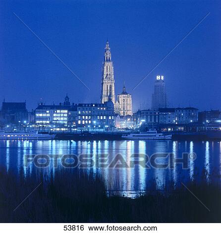 Stock Photograph - Town lit up at waterfront during night, Antwerpen, Belgium . Fotosearch