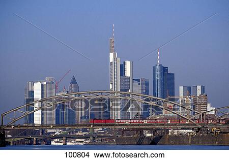 Picture - Train crossing bridge with city skyline in background, Frankfurt, Germany . Fotosearch