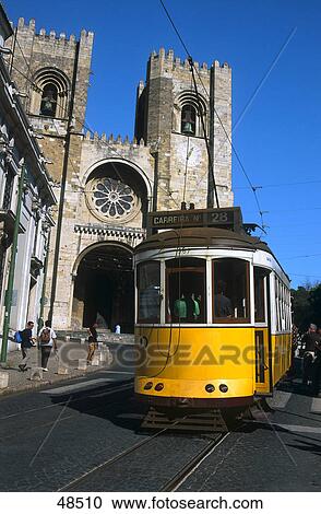 Stock Image - Tram passing by church, Se Patriarcal Cathedral, Lisbon, Portugal . Fotosearch