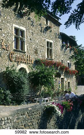 Stock Image - Two people sitting in front of a store, Mirmande, Drome, France . Fotosearch