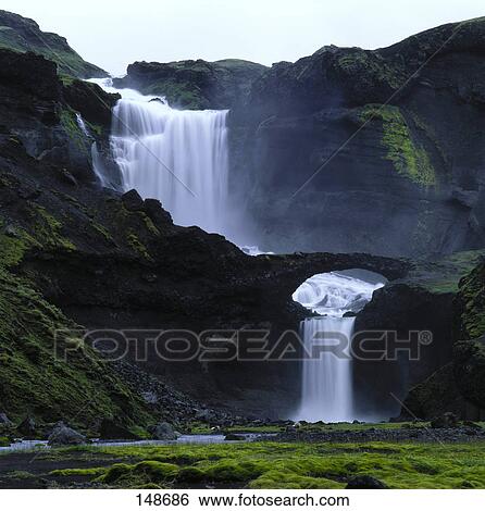 Stock Photograph - Waterfall and nature bridge, Eldgja fire ravine, Ofaerufoss, Iceland . Fotosearch