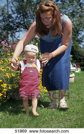 Woman helping her baby to walk in garden View Large Photo Image Stock Photo - Woman helping her baby to walk in garden . Fotosearch