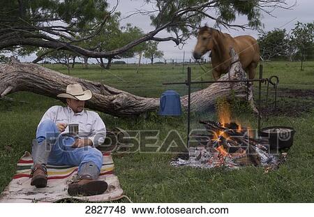 Cowboy resting beside a campfire, full shot View Large Photo Image Stock Photo - Cowboy resting beside a campfire, full shot . Fotosearch