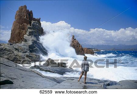 Female tourist looking at waves crashing on the coast, Rock formations on the cost, Arbatax, Tortoli, Sardinia, Italy View Large Photo Image Stock Photo - Female tourist looking at waves crashing on the coast, Rock formations on the cost, Arbatax, Tortoli, Sardinia, Italy . Fotosearch