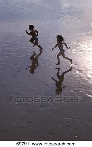 Stock Image - High angle view of boy and girl running on beach . Fotosearch