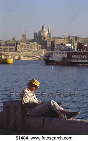 Picture - Man reading book at harbor, Valetta, Malta . Fotosearch