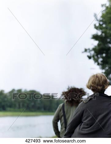 Rear view of two people strolling near river View Large Photo Image Stock Image - Rear view of two people strolling near river . Fotosearch