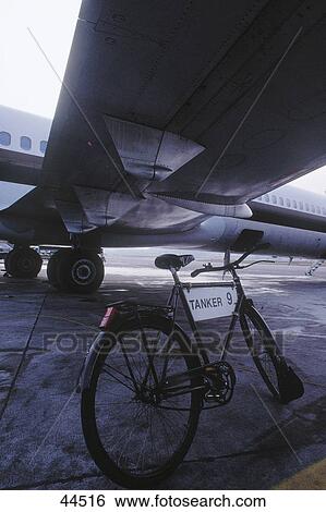Bicycle parked under airplane's wing at airport View Large Photo Image Stock Photograph - Bicycle parked under airplane's wing at airport . Fotosearch