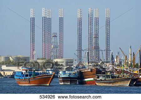 Stock Photograph - Boats with oil rigs on harbor, Sharjah, United Arab Emirates . Fotosearch