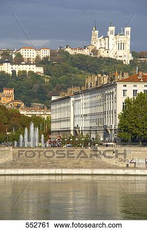 Stock Image - Buildings at riverbank with church on hill, Notre Dame De Fourviere, Rhone River, Lyon, Rhone-Alpes, France . Fotosearch