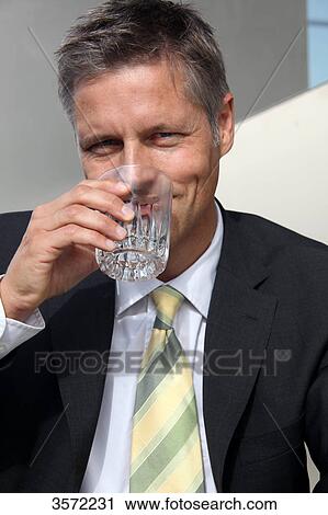 Businessman drinking water from glass, portrait View Large Photo Image Stock Image - Businessman drinking water from glass, portrait . Fotosearch