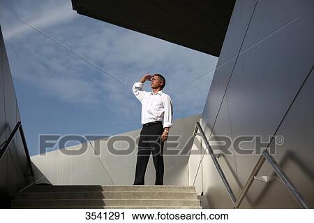 Stock Image - Businessman outdoors looking up . Fotosearch