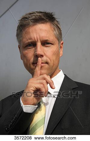 Businessman putting his finger on the mouth, portrait View Large Photo Image Stock Photo - Businessman putting his finger on the mouth, portrait . Fotosearch