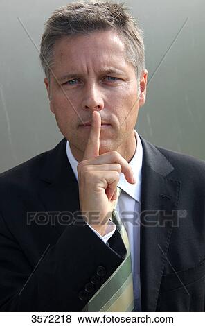 Stock Photo - Businessman putting his finger on the mouth, portrait . Fotosearch