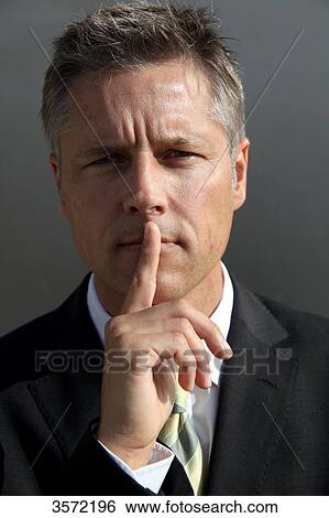 Stock Photograph - Businessman putting his finger on the mouth, portrait . Fotosearch