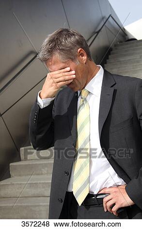 Stock Photo - Businessman standing with hand on his face . Fotosearch