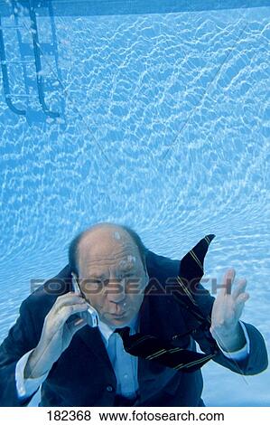Stock Photo - Businessman using mobile phone in swimming pool, elevated view . Fotosearch