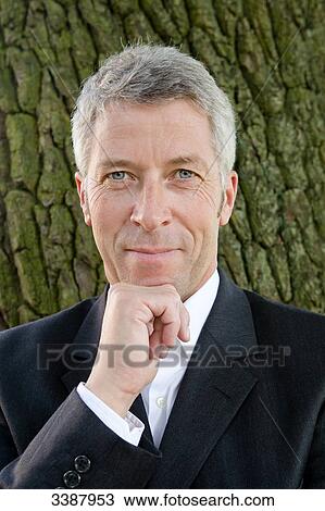 Businessman with hand on chin, portrait  View Large Photo Image Stock Image - Businessman with hand on chin, portrait . Fotosearch