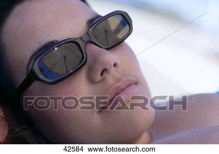 Close-up of a young woman wearing sunglasses View Large Photo Image Picture - Close-up of a young woman wearing sunglasses . Fotosearch