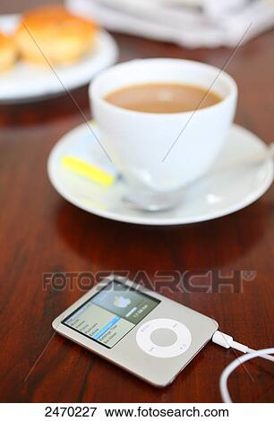 Stock Photo - Close-up of mp3 player and coffee cup on table . Fotosearch