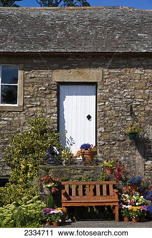Stock Image - Empty bench surrounded with potted plants, Kirkby Lonsdale, Combria, England . Fotosearch