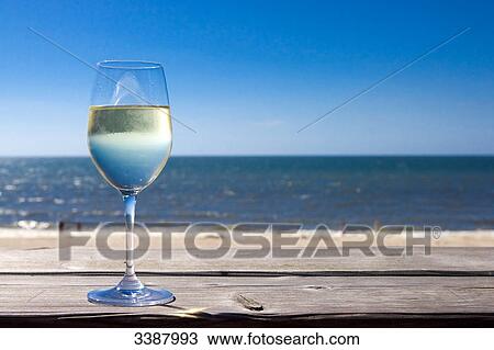 Glas of white wine on wooden board in front of sea, Wenningstedt-Braderup, Sylt, Germany View Large Photo Image Stock Image - Glas of white wine on wooden board in front of sea, Wenningstedt-Braderup, Sylt, Germany . Fotosearch