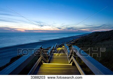 Stock Image - Illuminated footbridge on dunes at the North Sea coast, Wenningstedt-Braderup, Sylt, Germany, elevated view . Fotosearch