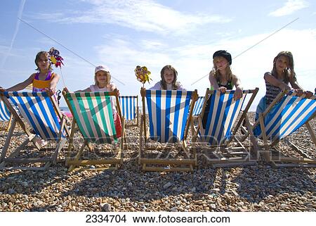 Kids sitting on striped sunloungers at the beach View Large Photo Image Picture - Kids sitting on striped sunloungers at the beach . Fotosearch