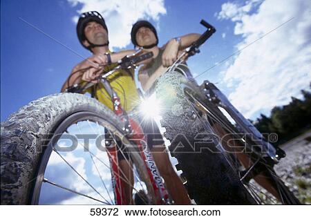 Low angle view of couple with bicycles View Large Photo Image Stock Image - Low angle view of couple with bicycles . Fotosearch