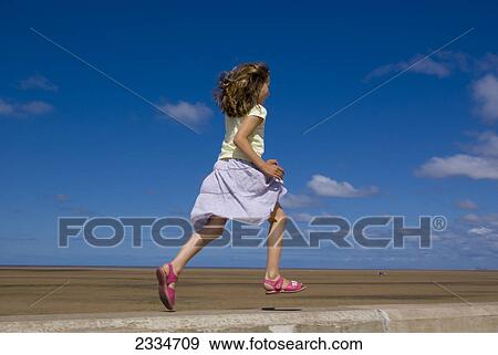 Low angle view of running girl in dress and sandals View Large Photo Image Stock Photo - Low angle view of running girl in dress and sandals . Fotosearch
