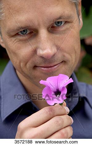 Stock Photo - Man holding blossom outdoors, portrait . Fotosearch