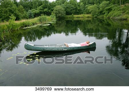Man lying in a canoe on a pond, elevated view View Large Photo Image Stock Photo - Man lying in a canoe on a pond, elevated view . Fotosearch