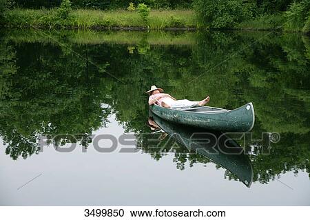 Man lying in a canoe with strawhat on his face, elevated view View Large Photo Image Stock Image - Man lying in a canoe with strawhat on his face, elevated view . Fotosearch