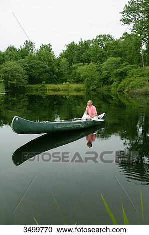 Man sitting in a canoe on a pond, elevated view View Large Photo Image Stock Image - Man sitting in a canoe on a pond, elevated view . Fotosearch