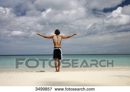 Man standing on the beach with outstretched arms, Paradise Island, Bahamas, rear view View Large Photo Image Stock Photo - Man standing on the beach with outstretched arms, Paradise Island, Bahamas, rear view . Fotosearch