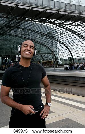 Stock Image - Man with MP3 player and headphones at a railway station platform . Fotosearch