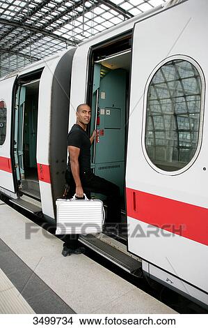 Picture - Man with suitcase boarding train . Fotosearch