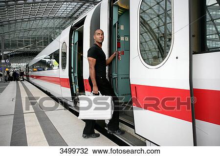 Stock Image - Man with suitcase boarding train . Fotosearch