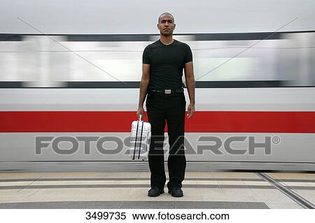 Man with suitcase standing at railway station platform in front of a train, front view View Large Photo Image Stock Photography - Man with suitcase standing at railway station platform in front of a train, front view . Fotosearch
