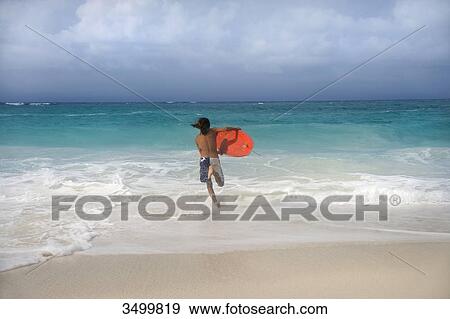Man with surfboard running in the water, Paradise Island, Bahamas, rear view View Large Photo Image Stock Photo - Man with surfboard running in the water, Paradise Island, Bahamas, rear view . Fotosearch