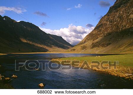 Stock Image - Mountains at riverbank, Glencoe, Highlands Region, Scotland . Fotosearch