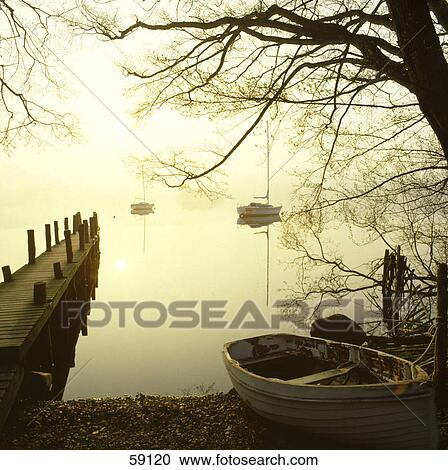 Stock Image - Pier in lake water at dusk, Lake District, Cumbria, England . Fotosearch